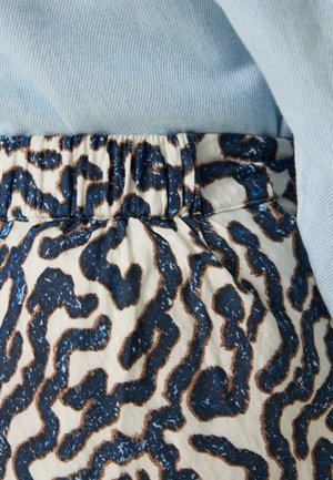 Elastische tailleband met een crèmekleurige basis met een abstract patroon in donkerblauw en bruin; gecombineerd met een lichtblauwe stof erboven.