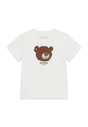 T-shirt blanc à manches courtes avec un motif visage d'ours brun souriant et le mot ""GUESS"" imprimé en dessous.