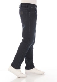 Jeans de mezclilla azul oscuro con corte recto, que presentan cinco bolsillos, una cinturilla texturizada y un sutil logotipo en el bolsillo trasero.