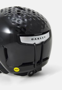 Zwarte skikop met een glanzend hexagonaal patroon, zilveren accenten, een MIPS-label en een verstelbare band voor een veilige pasvorm.