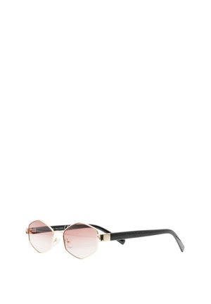 Occhiali da sole esagonali con montatura in metallo dorato, lenti a gradiente rosa e bracci neri curvi appoggiati su una superficie bianca.