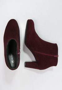 Bordeauxfarvede ankelstøvler i ruskind med lynlås i siden, rundet tå og blokhæl, med en tekstureret sål for bedre greb.