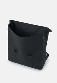 Sac messager noir avec une finition douce et mate, doté d'un grand haut ouvert, de deux sangles latérales et d'un intérieur texturé.