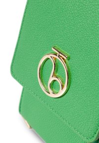 Borsa a tracolla verde con un accento di logo circolare dorato. Presenta una superficie liscia e una forma strutturata, adatta all'uso quotidiano.