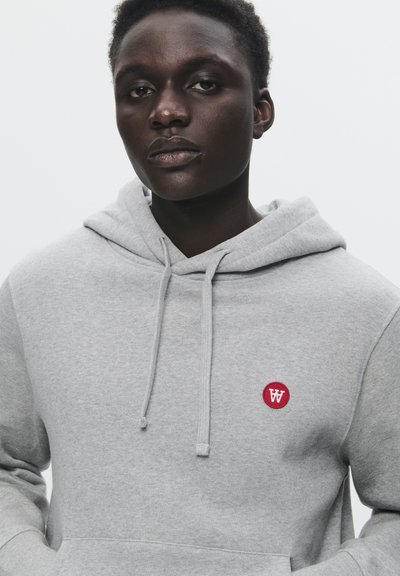 Hellgrau Kapuzenpullover mit Kängurutasche und kleinem roten runden Logo, das ein weißes "W" zeigt. Weicher Stoff, verstellbare Kordeln.