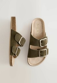 Olijfgroene suède sandalen met twee verstelbare strapsluitingen en goudkleurige gespen. Bruine kurken voetbed en gladde tan voering.