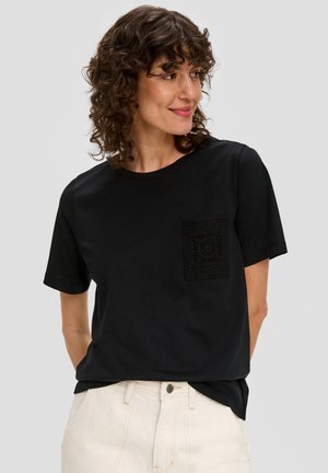 Zwarte katoenen T-shirt met korte mouwen, voorzien van een gehaakte pocket aan de linkerkant. Rechte snit, losse pasvorm.