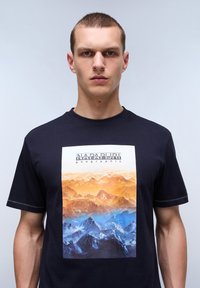 Námořnické tričko s grafickým potiskem hor v odstínech oranžové, žluté a modré. Má krátké rukávy a design s kulatým výstřihem.