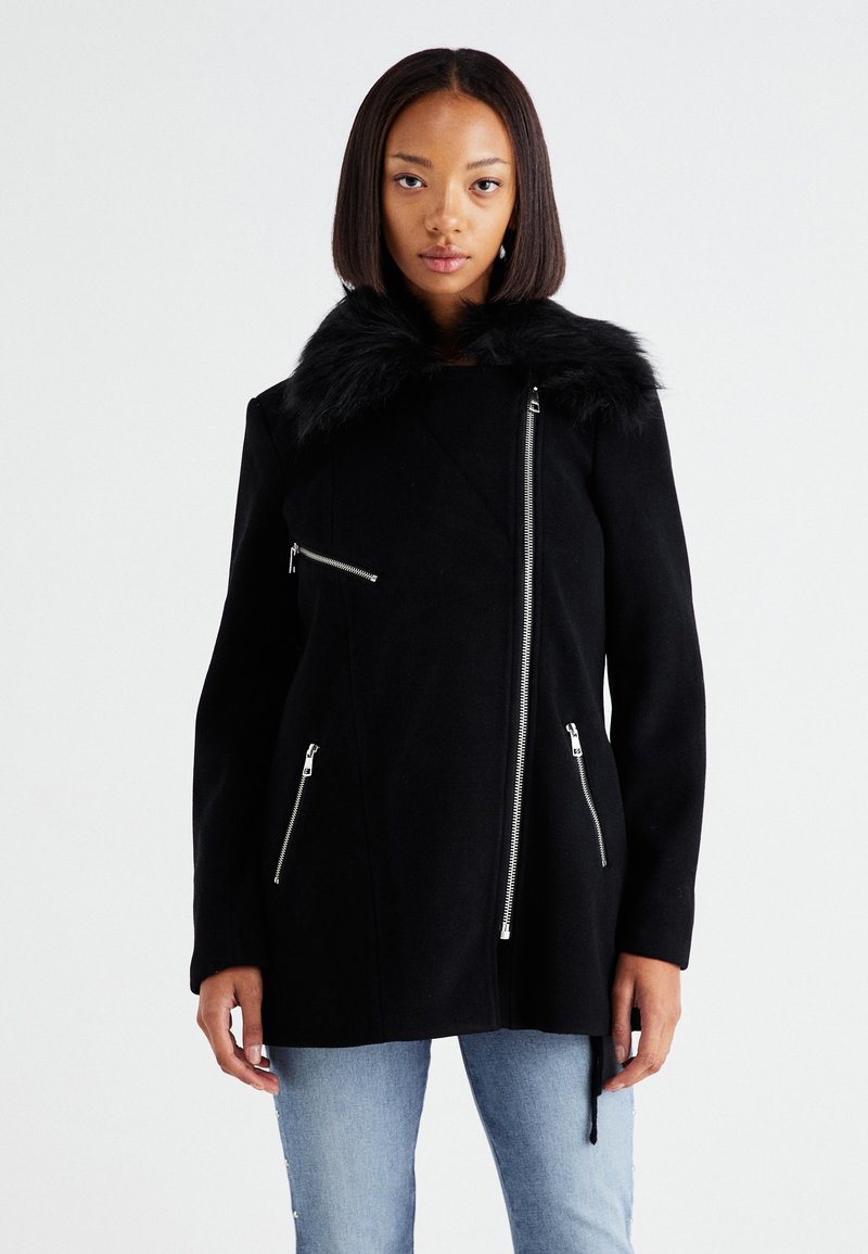 Čierny vlnený kabát s golierom z umelého kožušiny, asymetrickým zipsom a dvojicou predných vreciek na zips. Dlhé rukávy s hladkou textúrou.