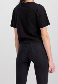 Mustat lyhythihaiset cropped-t-paidat, valmistettu pehmeästä kankaasta. Yhdistettyt tummiin slim fit -farkkuihin. Yksinkertainen, puhdas muotoilu, ilman näkyviä kuvioita tai yksityiskohtia.