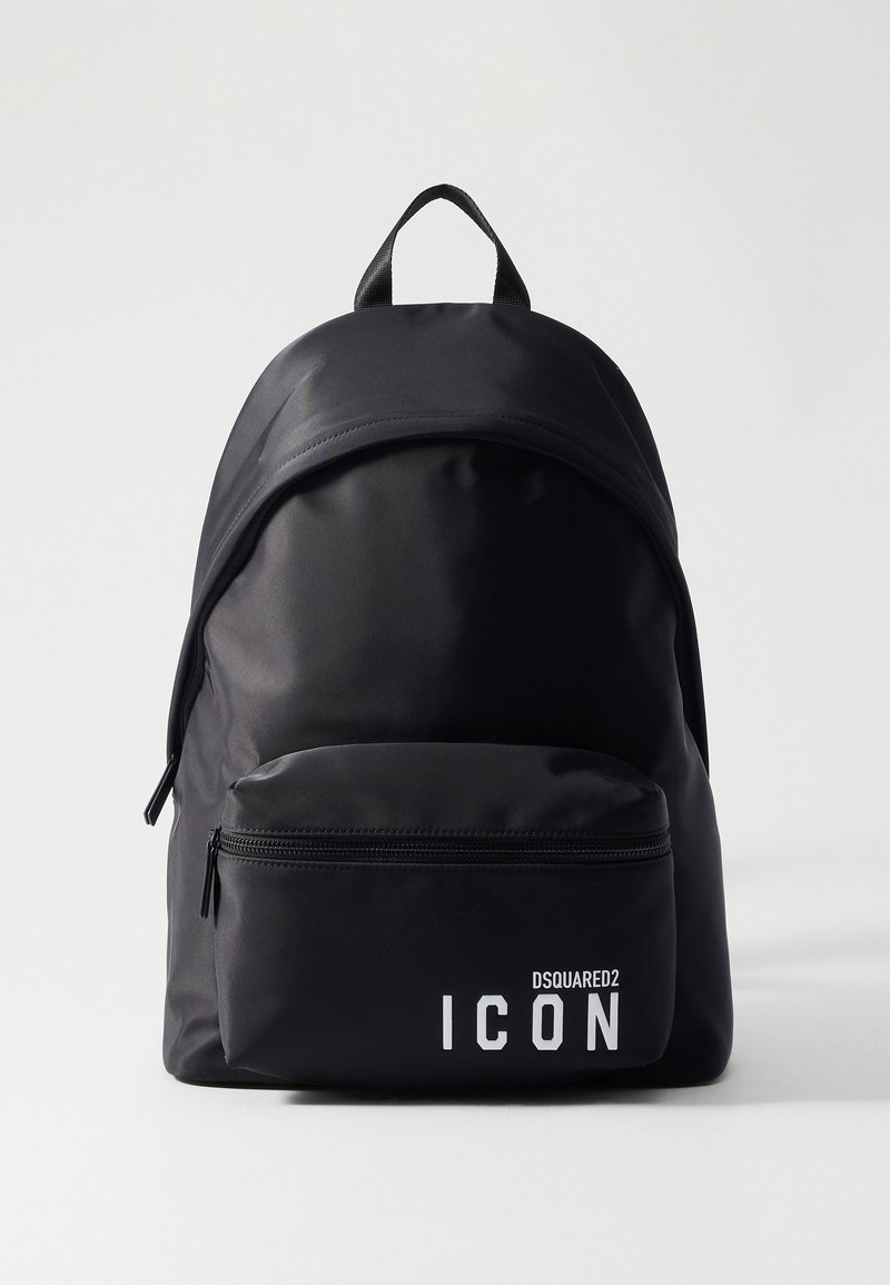 Sac à dos noir en nylon avec un dessus arrondi, une poche zippée à l'avant et un logo "ICON" blanc. Comprend une poignée supérieure et des bretelles ajustables.