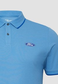 Lichtblauwe polo met twee zwarte knopen, donkerblauwe afwerking op de kraag en mouwen, en een klein blauw Ford-logo op de borst.