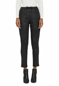 Black slim-fit pants with a textured finish, featuring a drawstring waist and two zippered side pockets. Paired with black ankle boots.