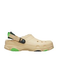 Beige klipklapper med en tekstureret overflade, der har ventilationshuller, en blød foring, justerbar rem og grønne samt sorte sålaccenter.
