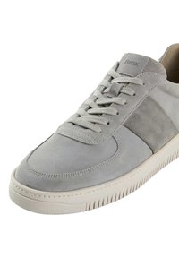 Graue Wildledersneaker mit einer glatten Textur, ausgestattet mit Schnürdesign, gepolsterter Zunge und gummierter Sohle mit horizontalen Rillen für besseren Halt.