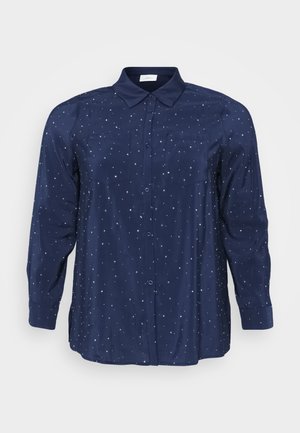 Blouse bleu marine en tissu doux, avec un devant à boutons, un col, deux poches poitrine et un motif d'étoiles avec des accents métalliques.