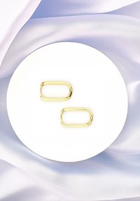Goldene ovalförmige Glieder liegen auf einer weißen runden Plattform, umgeben von sanftem, blassem blauen Stoff. Glatte Textur, glänzende Oberfläche.