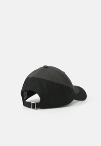 Svart og mørkegrå baseballcaps med buet visor, justerbar stropp bak, og diskré stikking på stoffet.