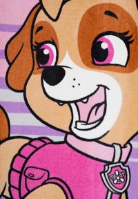 Coperta in pile rosa con un cane dei cartoni animati dal pelo marrone e bianco, grandi occhi espressivi e un gilet rosa con una distintivo. Sfondo a righe.