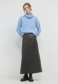 Hellblaue, gerippte Rollkragenpullover kombiniert mit einem langen schwarzen Lederrock. Bulky schwarze Stiefel runden das Outfit ab.