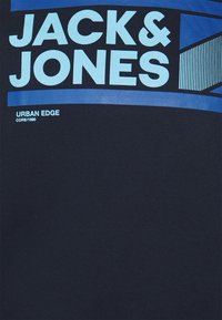 Tmavě modré bavlněné tričko s velkým světle modrým grafikou s nápisem "JACK & JONES" a geometrickými designovými akcenty.