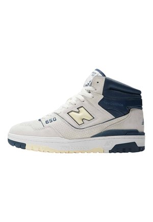 High-top sneaker in off-white suede with navy accents. Features perforated toe box, padded collar, and thick rubber sole with contrasting tread.