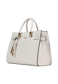 Sac fourre-tout en cuir blanc avec ferrures dorées, anses tressées et un pompon décoratif. Présente une forme structurée avec un bord contrastant.