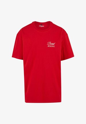 Sarkans kokvilnas T-krekls ar īsām piedurknēm, apaļu kaklu un uzdrukātu tekstu "Dead WRONG" baltā krāsā kreisajā priekšpusē.