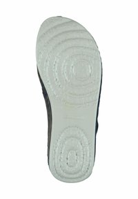 Shoe sole with textured white rubber, featuring circular tread patterns and branded detail. Upper part in dark material, minimalistic design.