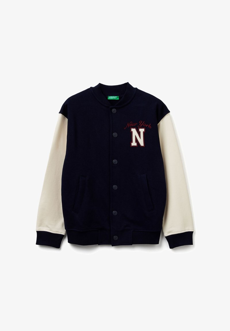 Veste universitaire bleu marine et crème avec col côtelé, boutons sur le devant et poches latérales. Présente "New York" et une lettre "N" brodées sur la poitrine.