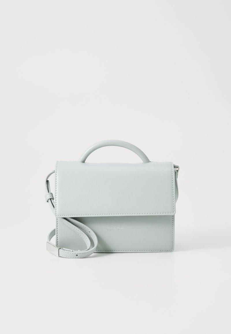 Sac à main en cuir bleu clair avec une poignée supérieure et une bandoulière amovible. Il possède une fermeture à rabat et un logo subtilement embossé.