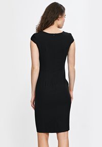 Czarna dopasowana sukienka z rękawami przykrótkimi, okrągłym dekoltem i zamkiem błyskawicznym z tyłu. Materiał jest gładki z delikatnym połyskiem, a sukienka posiada pionowe szwy.