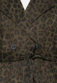 Brun djurmönstrad trenchcoat med midjebälte, utrustad med svarta knappar och en mjuk textur. Kännetecknande för sin dubbelknäppta design.
