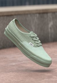Zapatillas de lona verde menta con una superficie texturizada, suela de goma y cordones prominentes; cuenta con una pequeña etiqueta "VANS" en el lateral.