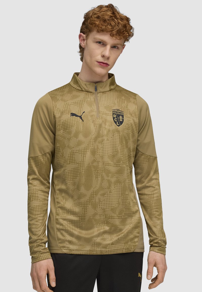 Langærmet pullover i olivengrøn med et tekstureret mønster. Har en kvart lynlås og et sort Puma-logo på brystet.
