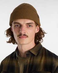 Brown ribbed knit beanie with a snug fit. Model wears a black and olive plaid shirt over a green t-shirt. Silver chain necklace visible.