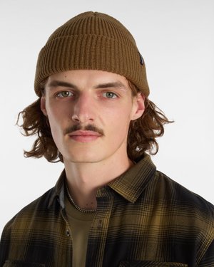 Gorro de punto acanalado marrón con un ajuste ceñido. El modelo lleva una camisa de cuadros negra y oliva sobre una camiseta verde. Se ve una cadena de plata.