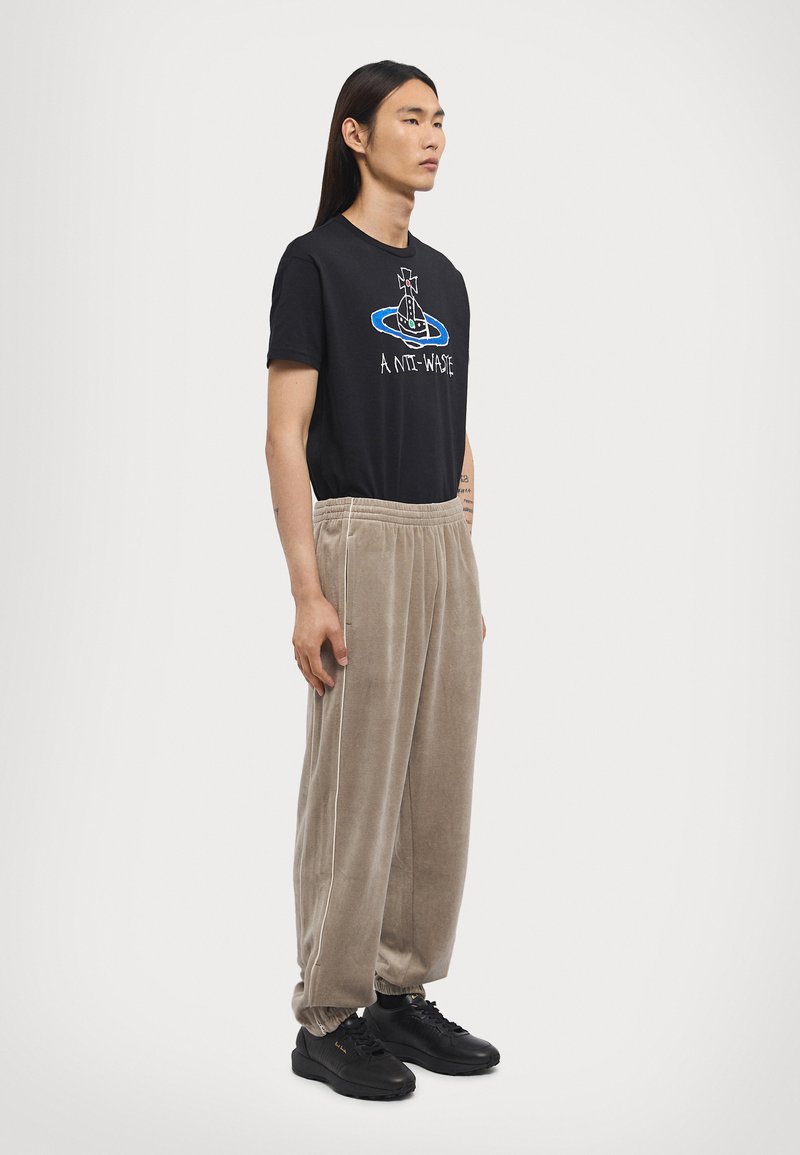 Black cotton t-shirt with graphic design, paired with beige corduroy pants featuring a tapered fit and elastic cuffs, complemented by black sneakers.