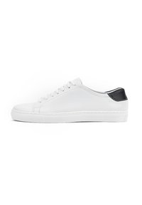 Białe skórzane sneakersy z płaską podeszwą, okrągłym noskiem i sześcioma oczkami do sznurowania. Czarny akcent na pięcie. Gładka tekstura z minimalnym zdobieniem.
