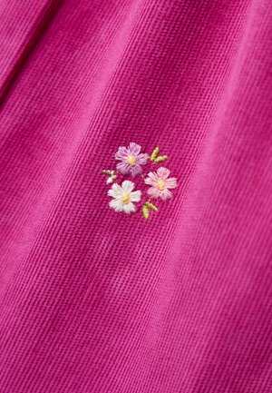 Rosa texturierter Stoff mit einem kleinen gestickten Cluster aus drei Blumen in Hellrosa, Weiß und Lila, umgeben von grünen Blättern.