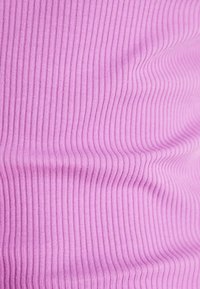 Tessuto a costine di colore rosa chiaro, caratterizzato da linee verticali. La trama appare morbida e elastica, adatta per abbigliamento aderente.