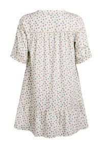 Vestido ligero y de corte holgado con un dobladillo con volantes. Fondo crema con lunares de colores en marrón, azul y verde. Mangas cortas.
