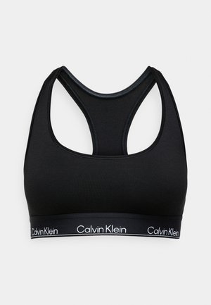 Musthave mustan spordibrassi pehmeast kangast, millel on raja tagasi disain. Alumisel serval on bränditud elastne riba valge logo tekstiga.