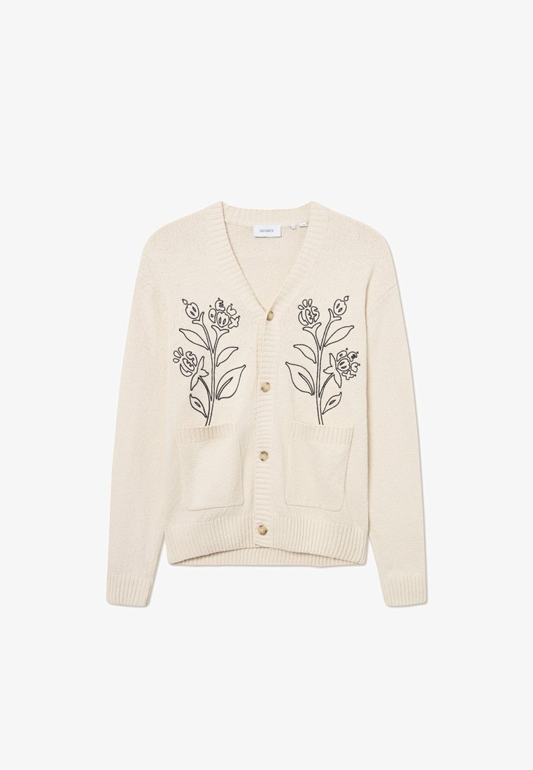 Kremfarget cardigan med blomsterbroderi, to frontlommer og ribbestrikkede mansjetter. Har V-hals og knappelukking. Myk tekstur.