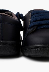 Scarpe in pelle blu con suole in gomma scura, punta rotonda e lacci blu scuro. Presentano dettagli ricamati e un collo morbido e imbottito.