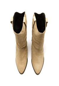 Botas vaqueras de ante beige con punta afilada y detalles bordados. Cuentan con tiradores en el tobillo y forro interior suave.