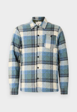 Quilted shirt jacket in blue, green, and beige plaid pattern. Features a button closure and a chest pocket with label accents.