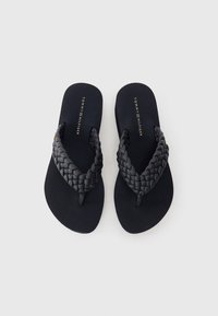 Crne japanke s pletenim trakama, glatkom mat podlogom i utisnutim logotipom. Jednostavan dizajn s sigurnim prianjanjem i minimalističkim stilom.