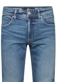 Jeans de denim en azul medio, con un diseño de cinco bolsillos, un desgaste sutil y costuras en contraste. Cierre de botón con cremallera.