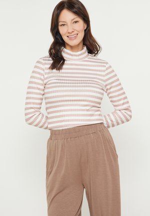 Maglietta a maniche lunghe a righe in rosa chiaro e bianco, con un collo alto. Abbinata a pantaloni beige a vestibilità ampia realizzati in tessuto morbido.